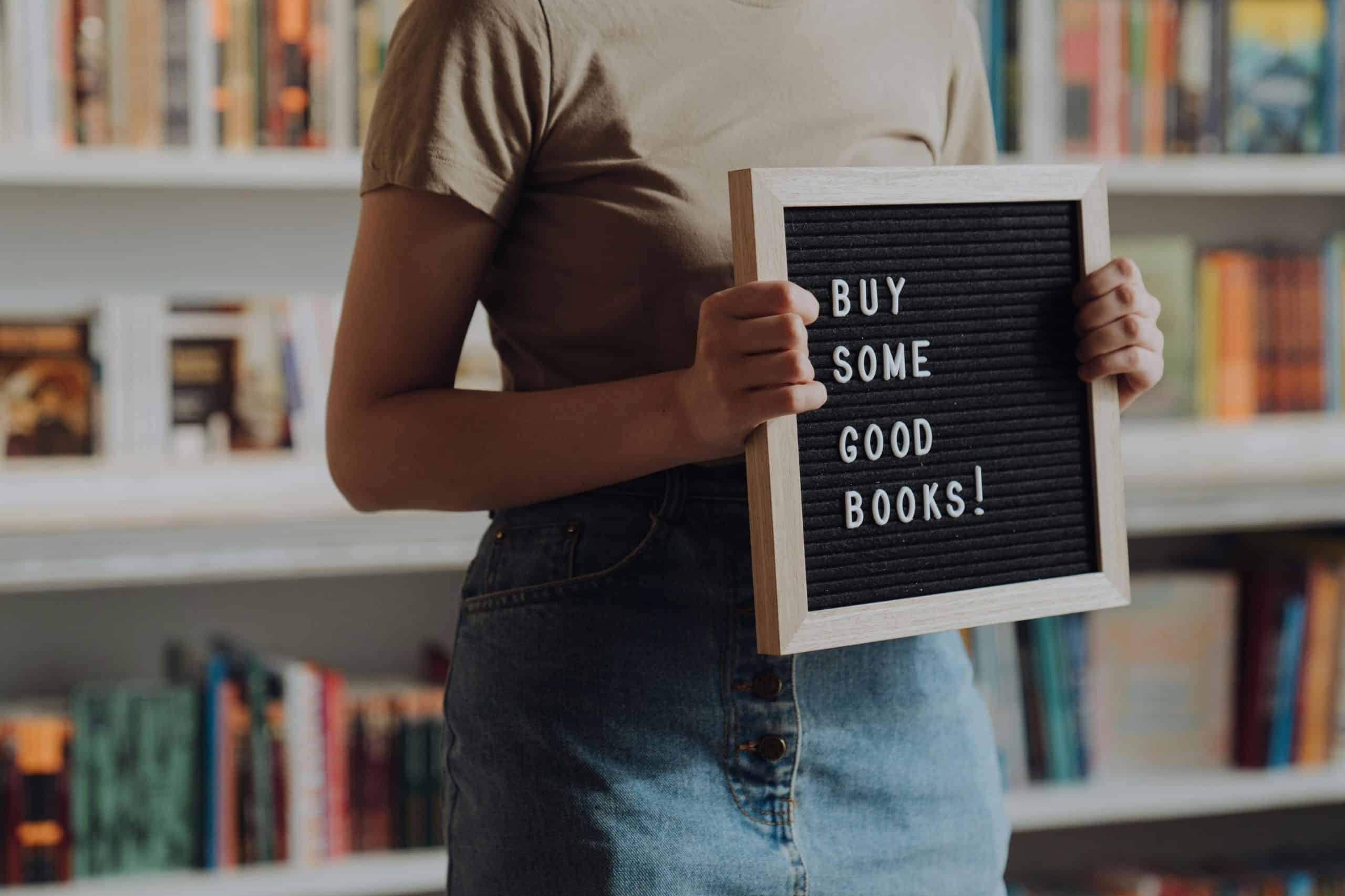 Personne tenant une pancarte avec message sur livres.